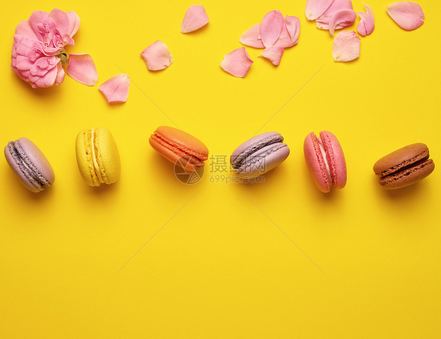 甜多色玉子奶油和粉红玫瑰芽花瓣散落于黄色背景顶视平面复制空间图片