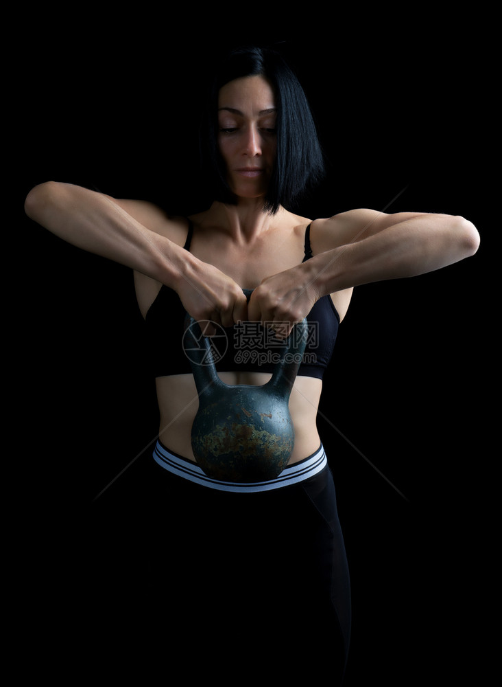 黑色头发的美丽运动女孩用两只手举起黑头发色背景上的金属重量体力锻炼图片