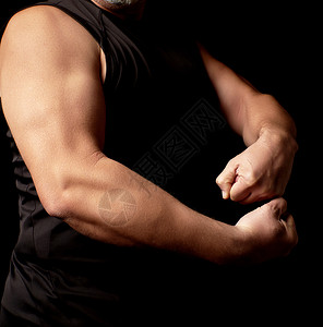 男子运动身穿黑衣手部肌肉紧张体健的男子体者展示他的二头肌低键图片
