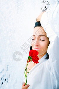 一位年轻女子的肖像她手上拿着一朵红玫瑰手被白窗帘环绕紧环绕清晨醒来图片