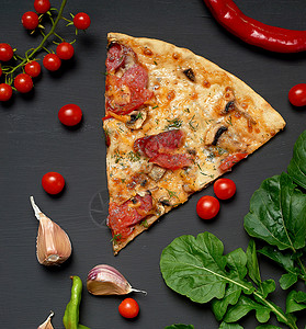 三角面包披萨片配蘑菇香肠西红柿和奶酪旁边是新鲜的青菜叶黑色背景平地图片