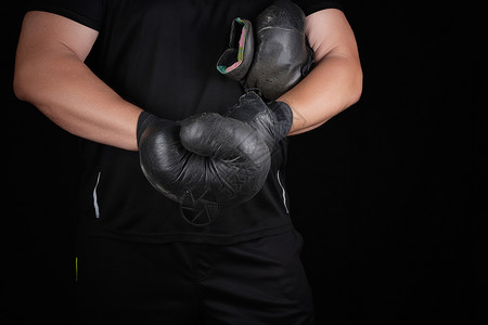 黑衣服的成年肌肉男在比赛前双手戴着黑色的拳手套双被裹在黑色运动绷带中图片