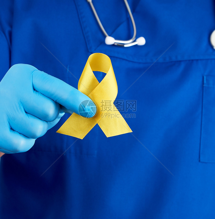身穿蓝制服的医生和无菌乳胶手套,上握着黄丝带,象征与猫肿瘤的斗争,问题及其预防,近距离结束。图片
