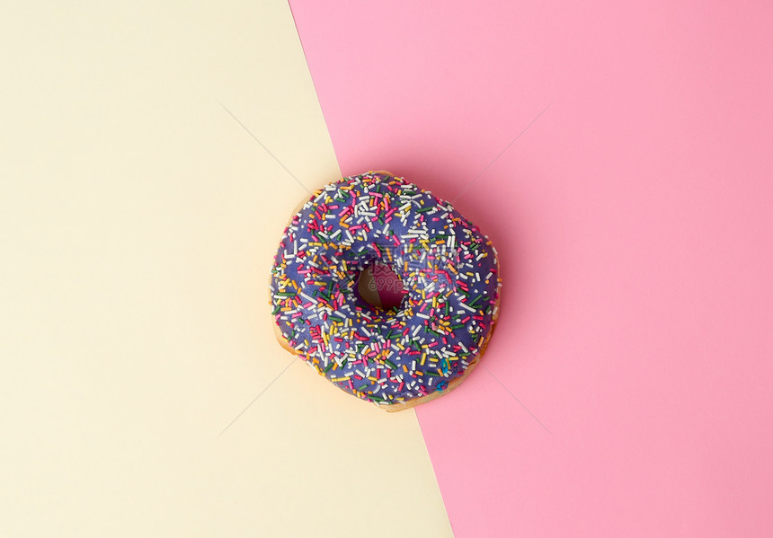 圆面包甜圈彩色糖喷洒在粉红黄背景上最高视图图片