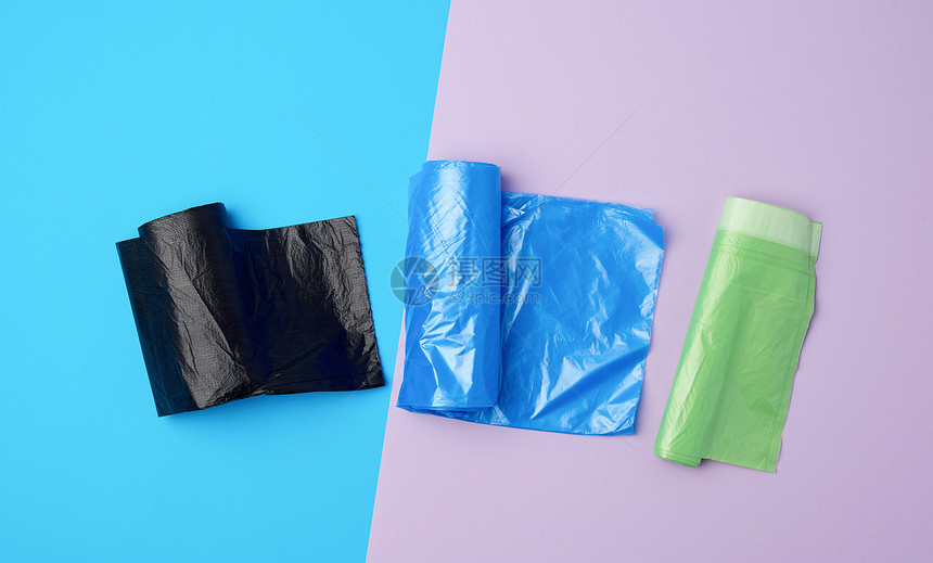 三卷装满塑料垃圾袋的卷子蓝色背景图片