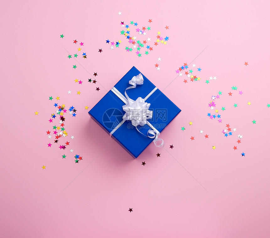 美丽的蓝色封闭盒白弓在粉红背景上有多色火花祝贺和惊喜的概念顶视图片