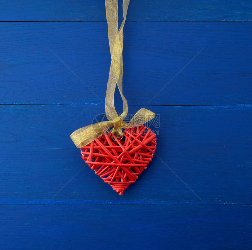 红色柳条装饰心形挂在丝绸金色丝带上蓝色木质节日背景为情人节图片
