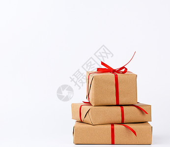 盒子里装满一堆礼物包裹在棕色的Kraft纸上绑在白色背景的红丝带上背景图片