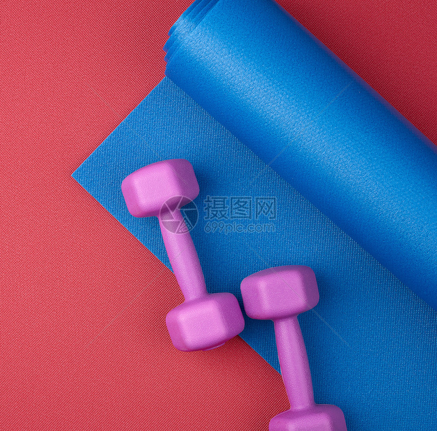 二对紫色塑料哑铃在蓝色新胎垫顶视训练设备上图片