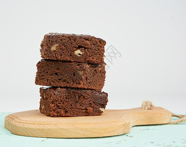 堆成的方形烤面包片巧克力蛋糕木板上加胡桃关门背景图片
