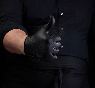 穿黑色制服和乳胶手套的男厨师展示了像批准手势关闭图片