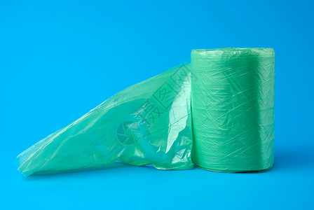 蓝色背景的垃圾桶绿色塑料袋滚关闭图片