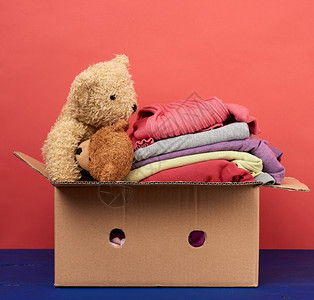 装满衣服和儿童玩具移动概念志愿和帮助的大型棕色纸箱装满衣服和儿童玩具图片