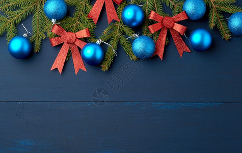 绿树枝圣诞蓝球和粉色红闪亮弓和木板上蓝背景的雕装饰背景图片