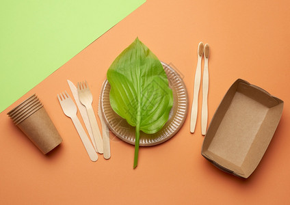 棕色手工艺纸和以橙绿色背景塑料排斥概念零废物的回收材料中废纸用具图片