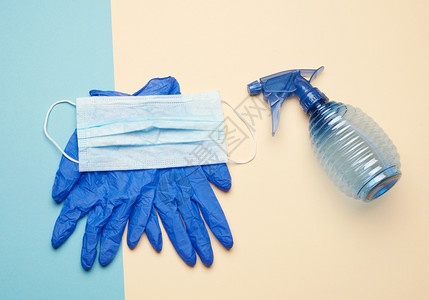 蓝手套和可重新使用的纺织品面罩蓝瓶用于蜜蜂色背景的消毒器顶视图片