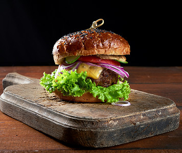 美味的汉堡包括炸牛肉切菜番茄生和洋葱烤白面条和芝麻种子图片
