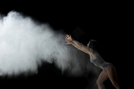 身穿黑色泳装运动服的美女正在黑底面粉的白云中跳舞烟喷射机飞起来图片
