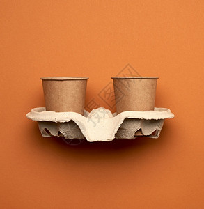 棕色手工艺纸和再生持有者以橙色背景最高视角塑料排斥概念零废物等形式提供的一次纸杯背景图片