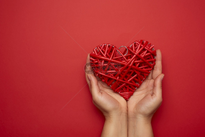 两只女手握着红胸心色背景爱情概念复制空间图片