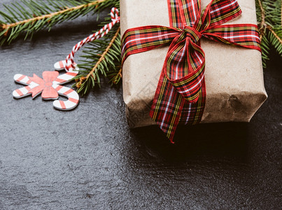 用棕色纸包着的长方形盒子绑上红丝带有弓黑色背景的礼物关上图片
