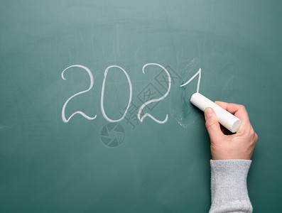 女手握着一块白粉笔在新年201的绿色学校董事会上写作背景