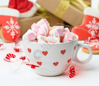 配有可和棉花糖的白陶瓷杯子放在礼物盒和圣诞玩具后面关门桌子高清图片素材