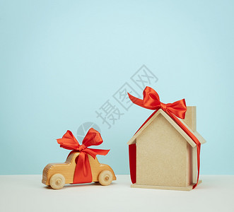 木制房屋和汽车玩具模型配有蓝色背景的红丝带房地产购买概念抵押贷款图片