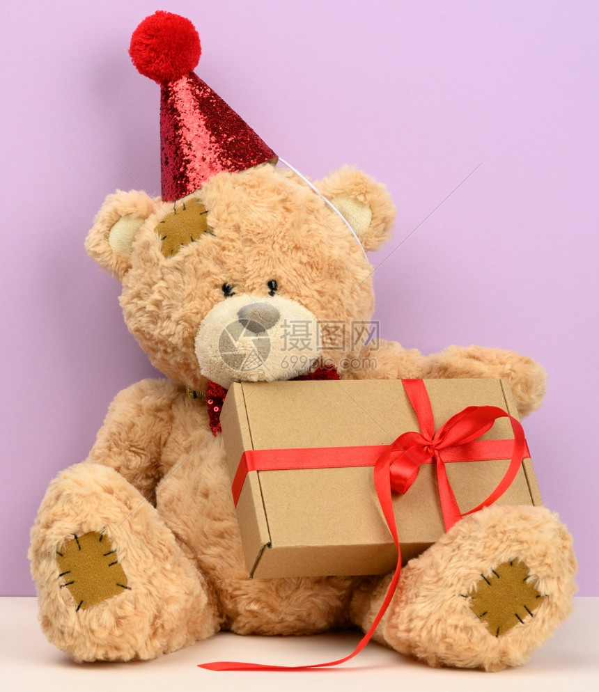 红帽子的棕色可爱泰迪熊坐着一个棕色盒子带着礼物喜庆背景图片
