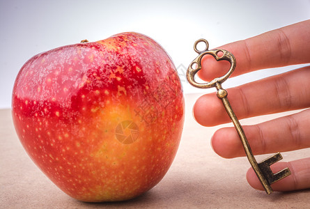 手握着红苹果旁边的钥匙秘密高清图片素材
