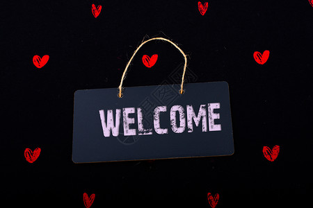 欢迎在黑通知牌上使用欢迎语红心环绕着背景图片