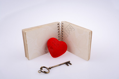 红色心脏和在空笔记本旁的一把钥匙图片