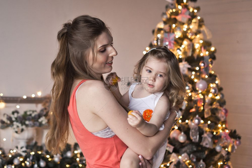 在圣诞节的装饰品上妈把她的女儿抱在怀里图片