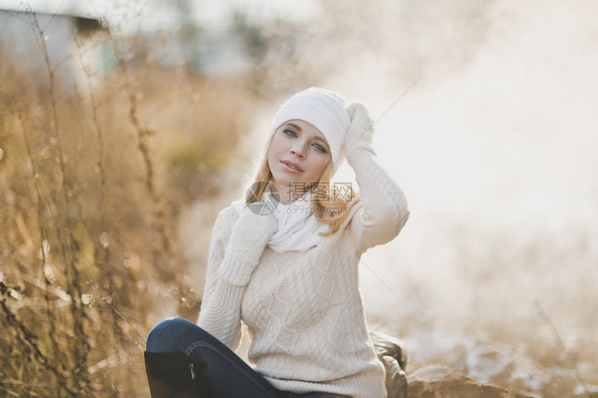 一位女孩坐在9186号公路旁边的一块大石头上冬季肖像图片