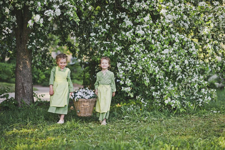 两个女孩拿着一篮花女朋友提了一个柳条篮子篮子里放着花用来装饰花园图片