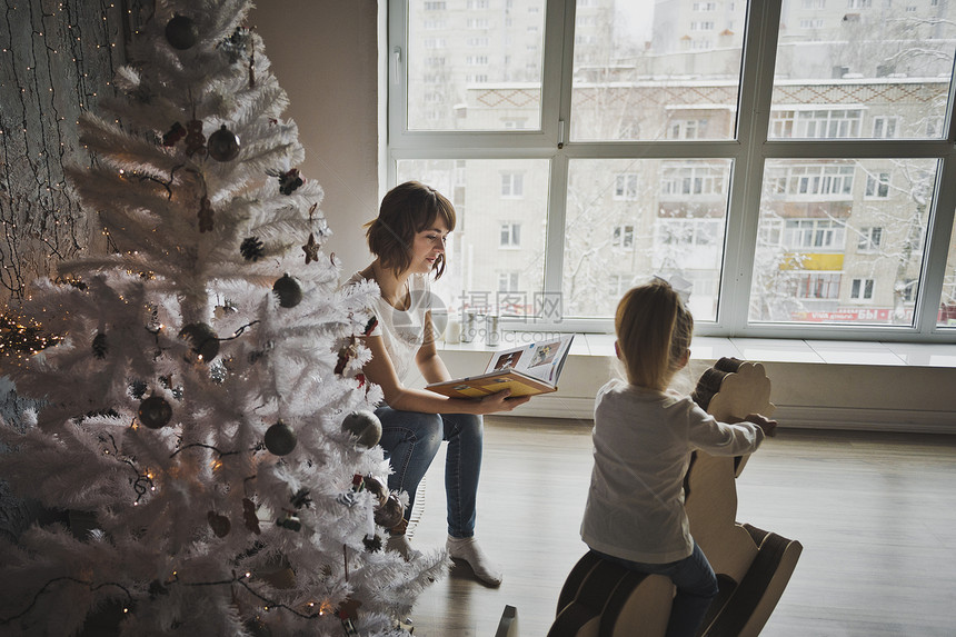 女儿和母亲在圣诞树周围玩耍母亲和女儿坐在圣诞树附近7084图片