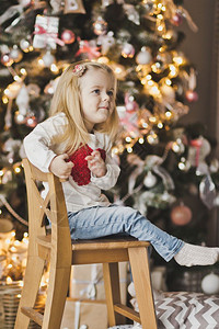 孩子坐在圣诞树旁的木椅上一个孩子的肖像画背景圣诞树装饰气球7294图片