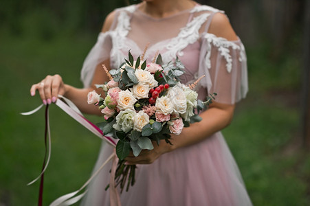 新娘双手触摸着一束美丽的精玫瑰花束上的丝带图片