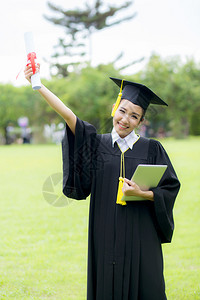 穿着毕业帽子和礼服并持有平板的女研究生图片