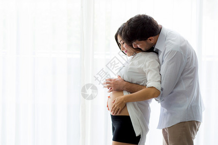 怀孕的妈和父亲站着抱肚子家庭概念图片