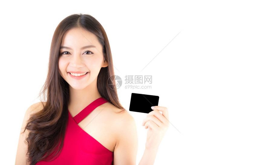 身着红裙子的亚洲年轻女持有信用卡想花很多钱与白种背景隔绝图片