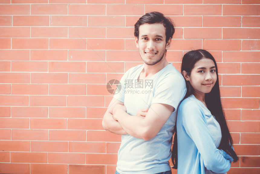 年轻一对有吸引力的亚裔男女肩膀交叉并微笑背靠在砖墙景上与浪漫男朋友和女充满自信浪漫概念图片