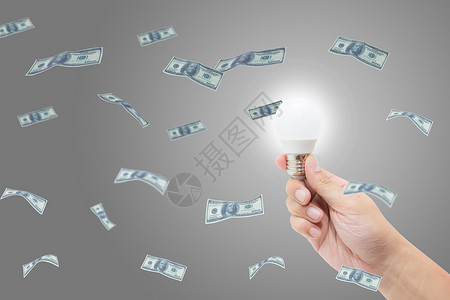 握着明亮灯泡的手有一个成功主意与货币美元金融业务概念图片