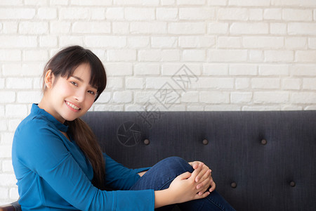 坐在沙发上笑的年轻女看着沙发上的摄影机房间高清图片素材