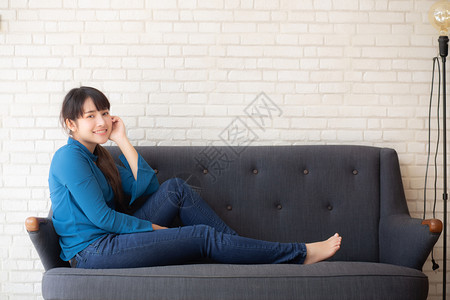 坐在沙发上笑的年轻女看着沙发上的摄影机室内的高清图片素材