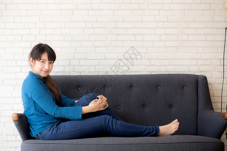 坐在沙发上笑的年轻女看着沙发上的摄影机新鲜的高清图片素材