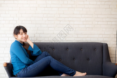 坐在沙发上笑的年轻女看着沙发上的摄影机成人高清图片素材