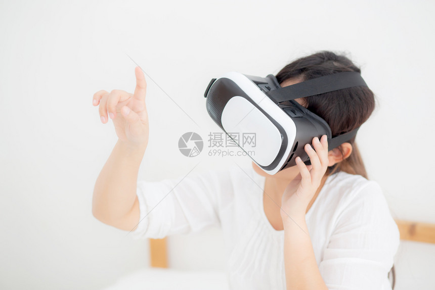 年轻美丽的女穿着虚拟现实头盔女孩装置观看模拟游戏娱乐图片