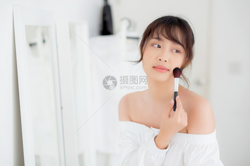 美容肖像年轻的女微笑面朝镜子化妆在卧室刷脸美丽的女孩抱着脸红皮肤护理和化妆品概念图片