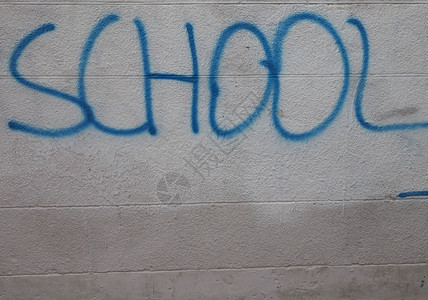 学校用蓝漆在灰墙上手工写成学校用墙上写成背景图片